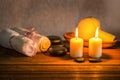 spa composition of white towels, candles with natural light, thai herbal compress ball in basket and zen basalt stones on wooden