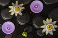 Spa concept of blooming passiflora flower, candles on zen basalt stones with drops in dark water, top view Royalty Free Stock Photo