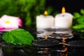 spa concept of green leaf hibiscus, plumeria with drops and candles on zen basalt stones in ripple reflection water, closeup Royalty Free Stock Photo