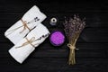 Spa concept. Lavender salt for a relaxing bath, aroma oil, white towels and dry lavender flowers on a black wooden background. Royalty Free Stock Photo