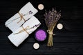 Spa concept. Lavender salt for a relaxing bath, candles, white towels and dry lavender flowers on a black wooden background. Royalty Free Stock Photo