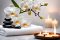 Spa concept, massage stones with towels, candles and white orchids. Royalty Free Stock Photo