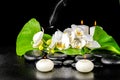 spa concept of orchid flower, phalaenopsis, leaf with dew, candles, smoke on black zen stones, closeup Royalty Free Stock Photo