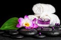 spa concept of orchid flower, zen basalt stones with drops, purple candles, beads and white towels, closeup Royalty Free Stock Photo