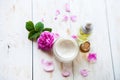 Spa concept with pot of moisturizing cream beautiful pink roses and rose essence oil on white wooden background Spa treatment. Royalty Free Stock Photo