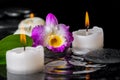 spa concept of purple orchid dendrobium, leaf with dew and candles on zen stones in ripple reflection water, closeup Royalty Free Stock Photo