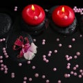 Spa concept of red candles on zen stones with drops, orchid Royalty Free Stock Photo