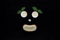 Spa wellness concept, face with eyes candles, a seashell nose and a mouth of a wooden body brush on black background