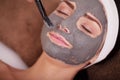 Spa concept. Young woman with nutrient facial mask in beauty salon, close up