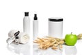Spa cosmetics, jar of cream, oil with wheat, white cosmetic bottles with apple and wheat towel, candle, soap isolated on