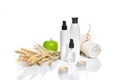 Spa cosmetics, jar of cream, oil with wheat, white cosmetic bottles with apple and wheat towel, candle, soap isolated on