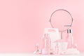 Spa cosmetics products and round mirror in pastel pink and silver color - cream, bath salt, essential oil, soap, bottle, bowl.