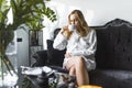 SPA day and relaxation concept. Young caucasian blond hair female client in white robe drinking hot beverage from a cup Royalty Free Stock Photo