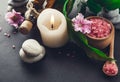 Spa essentials including candle, salt, stones, oil and green leaves