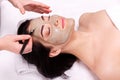 Spa facial mask application. Beautiful relaxed woman having clay face mask in the spa