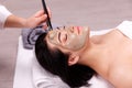 Spa facial mask application. Beautiful relaxed woman having clay face mask in the spa