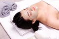 Spa facial mask application. Beautiful relaxed woman having clay face mask in the spa