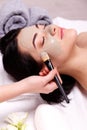 Spa facial mask application. Beautiful relaxed woman having clay face mask in the spa