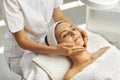 Spa facial massage. Beautician makes face massage to woman in white beauty salon Royalty Free Stock Photo