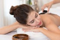 Spa hot stone massage. Beautiful woman lying on the bed relax with spa hot stone on her back Royalty Free Stock Photo