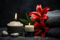 A spa-like composition featuring a contrasting black and white candle set amongst smooth stones, a radiant red lily