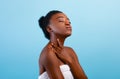 Daily spa. Millennial african american lady with towel touching her soft skin on neck, enjoying her young beauty