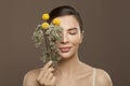 Spa model woman with perfect clear skin and flowers on brown background. Eyes closed. Herbal medicine and skincare concept Royalty Free Stock Photo