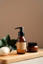 SPA natural organic cosmetics set on wooden board. Shower gel or shampoo amber glass dispenser bottle, jar of moisturizer cream, Royalty Free Stock Photo