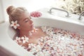 Spa Relax. Blonde enjoying bath with plumeria tropical flowers. Health And Beauty. Closeup Beautiful Sexy Girl Bathing With Petals