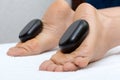 Woman lying on stomach, female masseuse doing legs and feet massage with hot stones Royalty Free Stock Photo