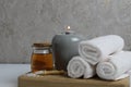 Spa relaxation home care. White towels candle oil for massage lie on a wooden tray on a gray background Royalty Free Stock Photo