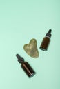 Spa salon kit made from green jade gua sha scraper and essential oil bottles. Gua sha massager and two essential oils on green Royalty Free Stock Photo