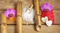 Spa set with multi-colored slides of sea bath salt, bamboo tubes and orchid flowers on a wooden background