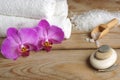 Spa set with white salt for bath, flowers of orchid and towels on a wooden background