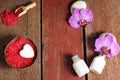 Spa set on a wooden table with red bath salt, lotion for skin and orchid flowers on stones, copy space for your text Royalty Free Stock Photo