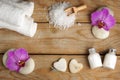 Spa set on a wooden table with white bath salt, lotion, towels and orchid flowers on stones Royalty Free Stock Photo