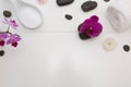 Spa setting with pink orchids, black stones on white wood background. Royalty Free Stock Photo