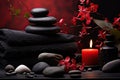 Spa still life with a black towel, red flowers, stones, a candle, and a bottle on a red background Royalty Free Stock Photo