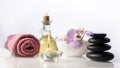 Spa still life composition on white background. Zen spa stones next to towel, burning candle, bottle with oil and bow Royalty Free Stock Photo