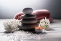 Spa still life with pyramid of zen stones,burning candle, sea salt, towel and white flowers on white wooden table Royalty Free Stock Photo