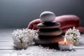 Spa still life with stack of stones,burning candle, sea salt, towel and white flowers on white wooden table Royalty Free Stock Photo