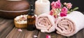 Spa still life with towels, rose oil bottle, rose flowers on wooden background, spa and wellness setting Royalty Free Stock Photo