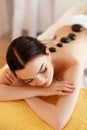 Spa Stone Massage. Young Woman Have Hot Stone Massage Treatments Royalty Free Stock Photo