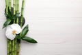 Spa stones, bamboo and orchid flower on light wooden table, flat lay. Space for text Royalty Free Stock Photo