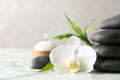 Spa stones, bamboo sprout, burning candle and beautiful orchid flower on white marble table, space for text Royalty Free Stock Photo