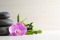 Spa stones, bamboo stems and beautiful orchid flower on white table, space for text Royalty Free Stock Photo