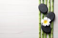 Spa stones, bamboo stems and plumeria flower on light wooden table, flat lay. Space for text Royalty Free Stock Photo