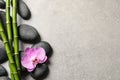 Spa stones, beautiful orchid flower and bamboo stems on light grey table, flat lay. Space for text Royalty Free Stock Photo