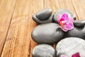 Spa stones and beautiful orchid flower on wooden background, closeup Royalty Free Stock Photo