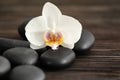 Spa stones with beautiful orchid flower on wooden background Royalty Free Stock Photo
